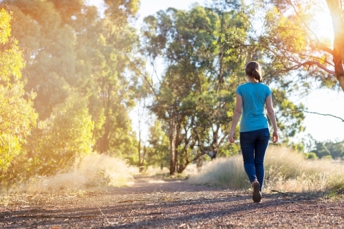 Young woman walking away on bush trail - Australian Stock Image