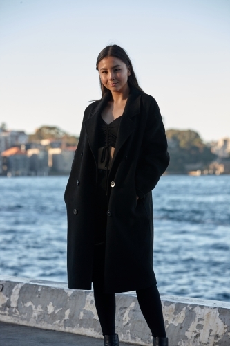 Young woman wearing coat by harbour
