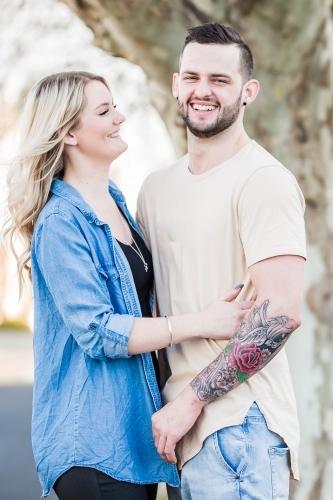 Young woman with arms around boyfriend laughing - Australian Stock Image