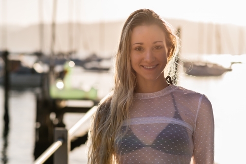 Young woman with blonde hair wearing black bikini smiling - Australian Stock Image