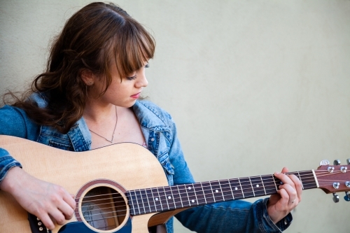 Young woman with guitar and light green copy space - Australian Stock Image