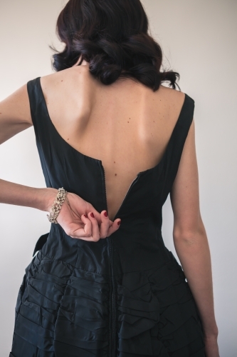 Young woman zipping the back of her formal dress - Australian Stock Image